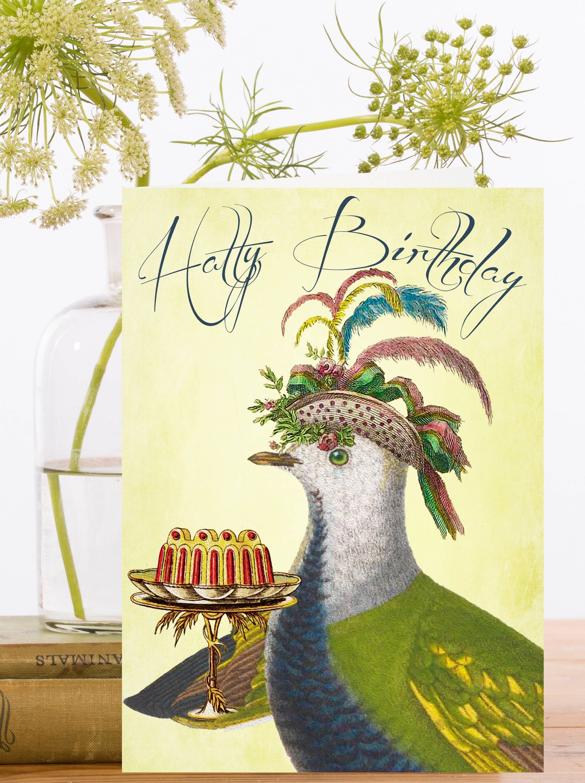 This fine feathered friend in their best hat wants to wish a very Hatty Birthday. A pigeon present a cake on a stand wearing fancy hat. With the words Hatty Birthday.