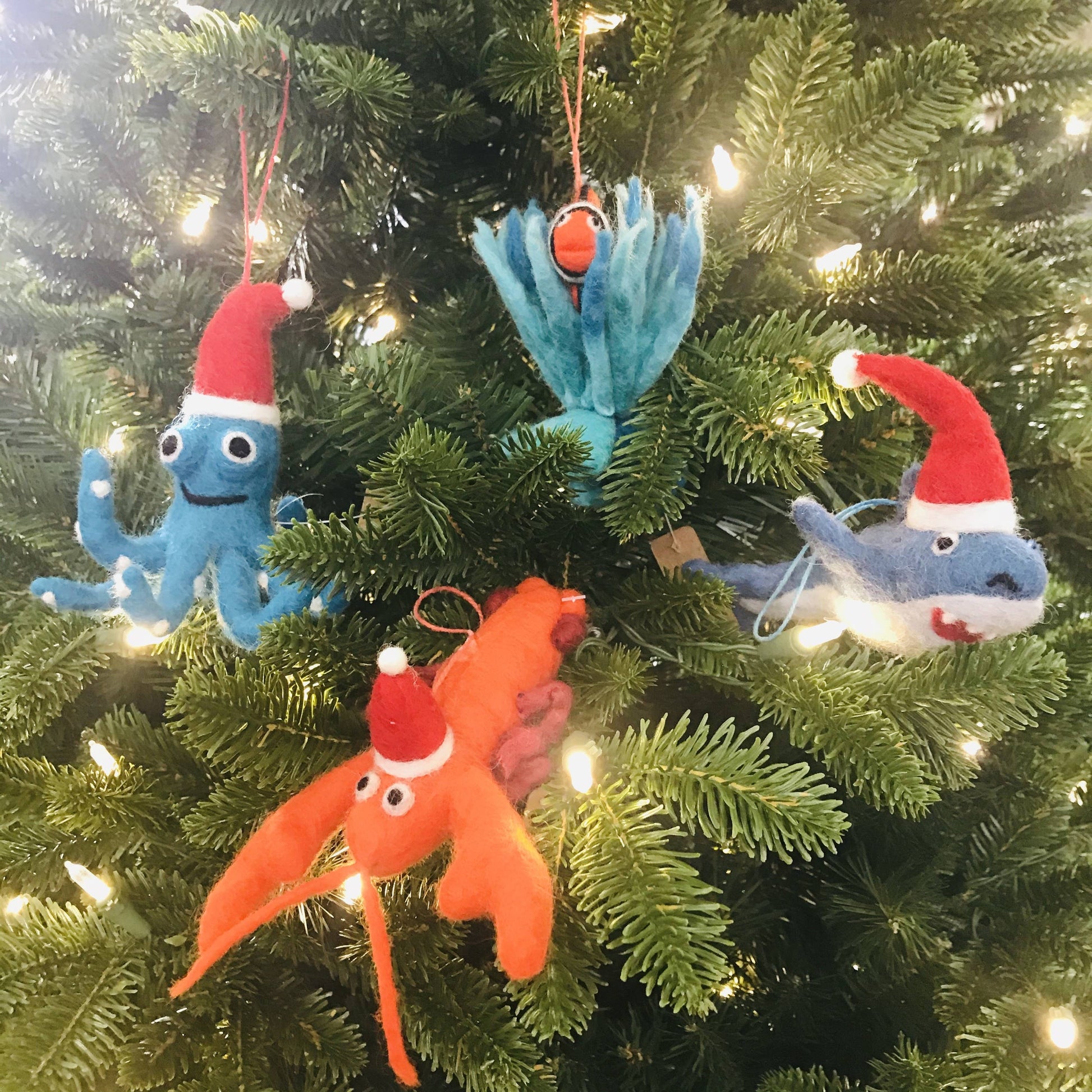 Handmade Felt Festive Lobster Tree Hanging decoration, wearing a red and white Santa hat. Shown on a tree with other Felt So Good Characters.