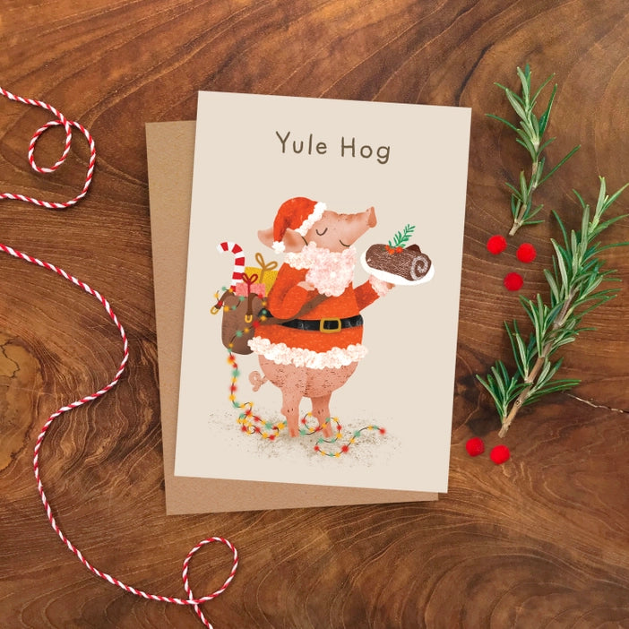 Yule Hog Christmas Card. Hog dressed up as Santa with a sackful of presents and holding a chocolate yule log