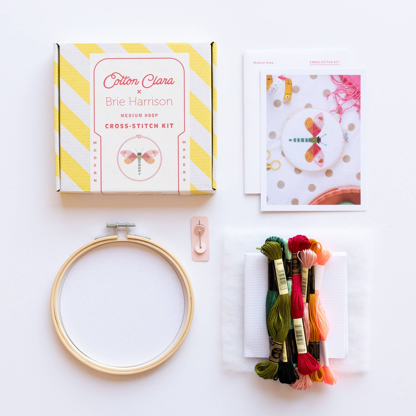 Showing the contents of the Dragonfly Cross Stitch Kit, which contains everything you would need except scissors. The Hoop, Aida, needles, pattern and instructions and thread.