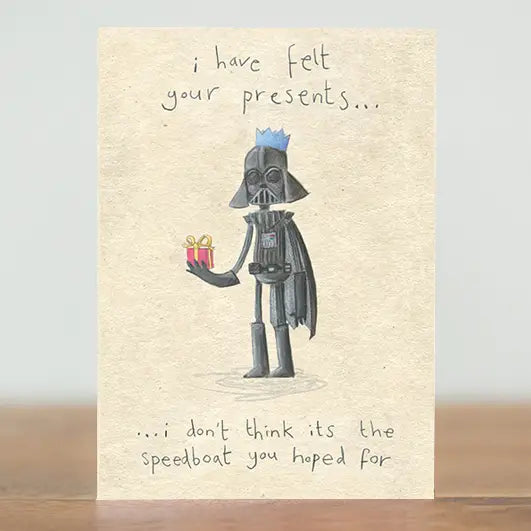 Darth Vadar, ruining the suspense of gift opening at Christmas again. Depicting Darth vadar holding a wrapped Christmas present and wearing a paper crown. With the words "I have felt your presents...I don't think its the speedboat you hoped for."