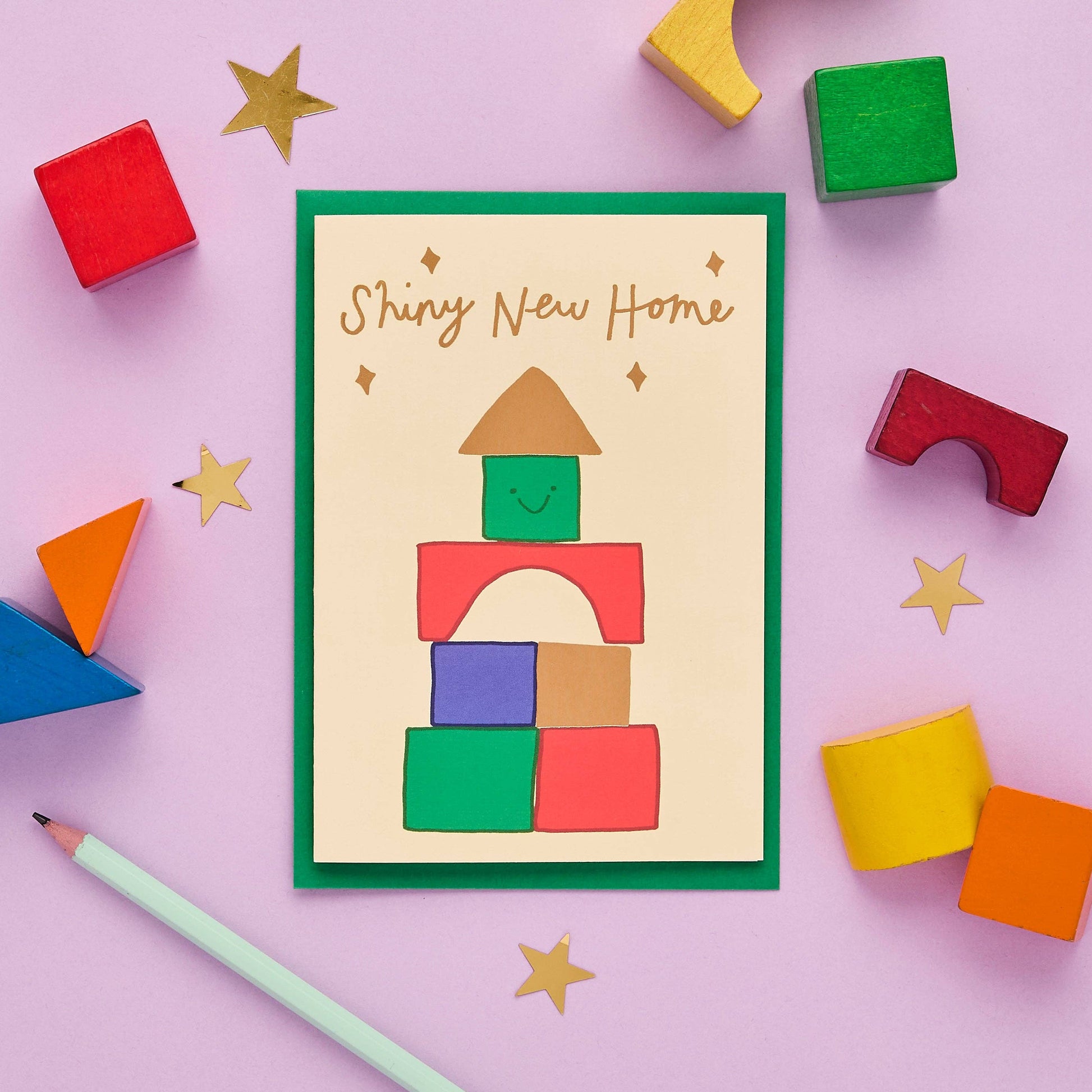 A happy new home card, but a bit different. This quirky, hand drawn greeting card celebrates a brand new abode with its fun illustration of a house built from colourful toy building blocks.

Printed in the UK on sustainably sourced premium, recyclable paper. Written in a striking, hand lettered font and finished with gold foil, the message on the front of this thoughtful card reads "Shiny new home"