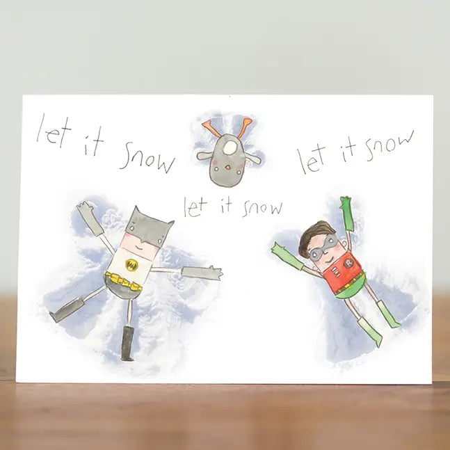 Tiny superheroes Batboy and Robin doing snow angels. Card says Let It Snow. Sustainably made in the UK.