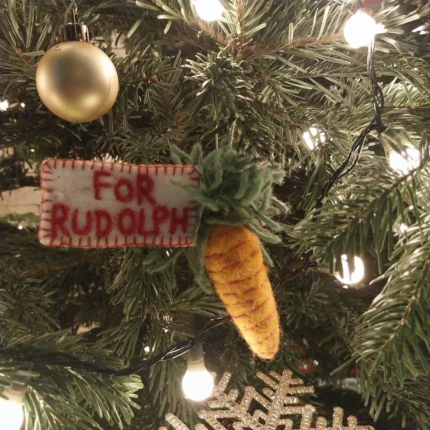 Handmade Felt Snack for Rudolph Christmas Decoration. A Felt carrot with a note attached with red font reading For Rudolph. Shown on a Christmas tree.