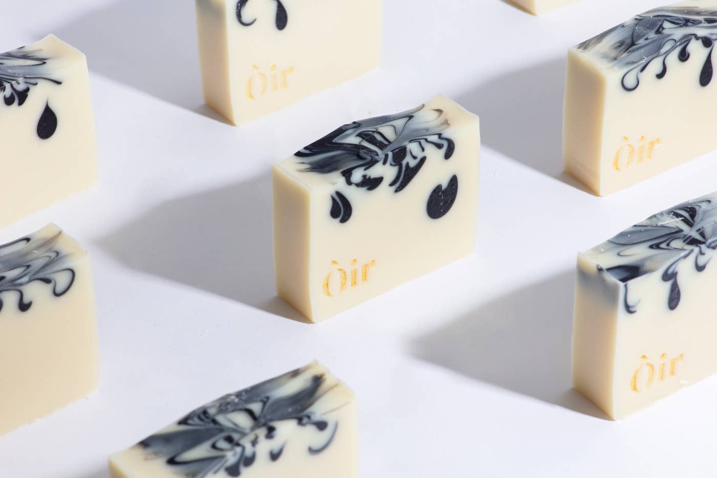 Cedarwood, Clary Sage, Rose Geranium and Vetiver Soap. Handmade in the UK. A sustainable replacement for shower gel. The soap is a cream bar with beautiful, gold lettering with the word OIR| and black swirls in the soap.