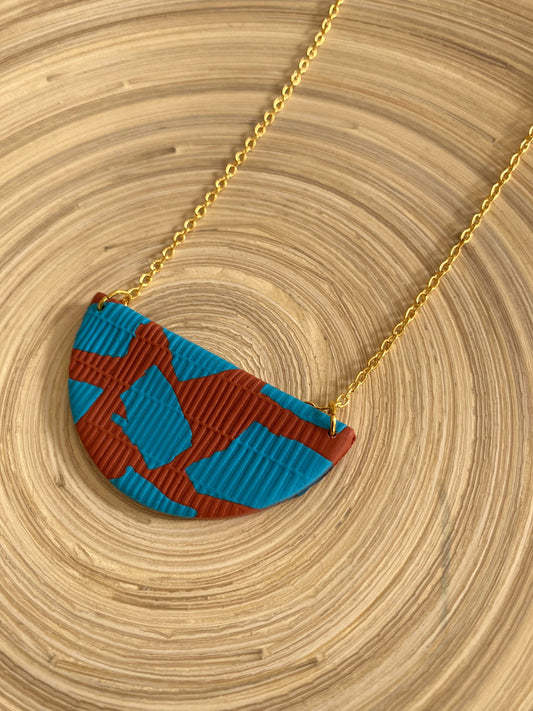 Handmade polymer clay necklace with gold leaf. No two pieces are ever exactly the same as they are all cut from a large designed piece of clay. Abstract shapes in turquoise and the background is terracotta. On a 22ct gold-plated brass chain.