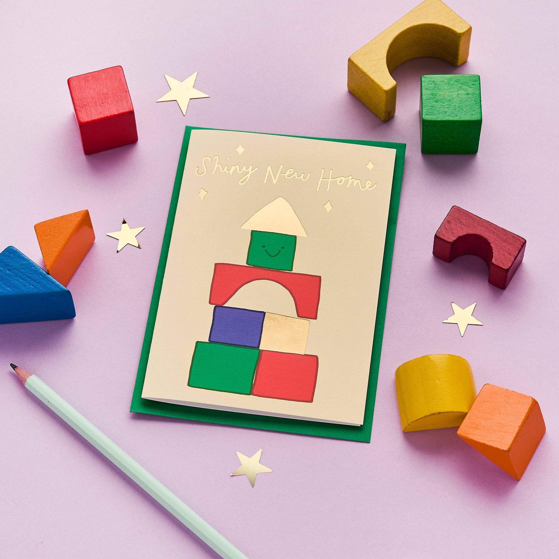 A happy new home card, but a bit different. This quirky, hand drawn greeting card celebrates a brand new abode with its fun illustration of a house built from colourful toy building blocks.

Printed in the UK on sustainably sourced premium, recyclable paper. Written in a striking, hand lettered font and finished with gold foil, the message on the front of this thoughtful card reads "Shiny new home"