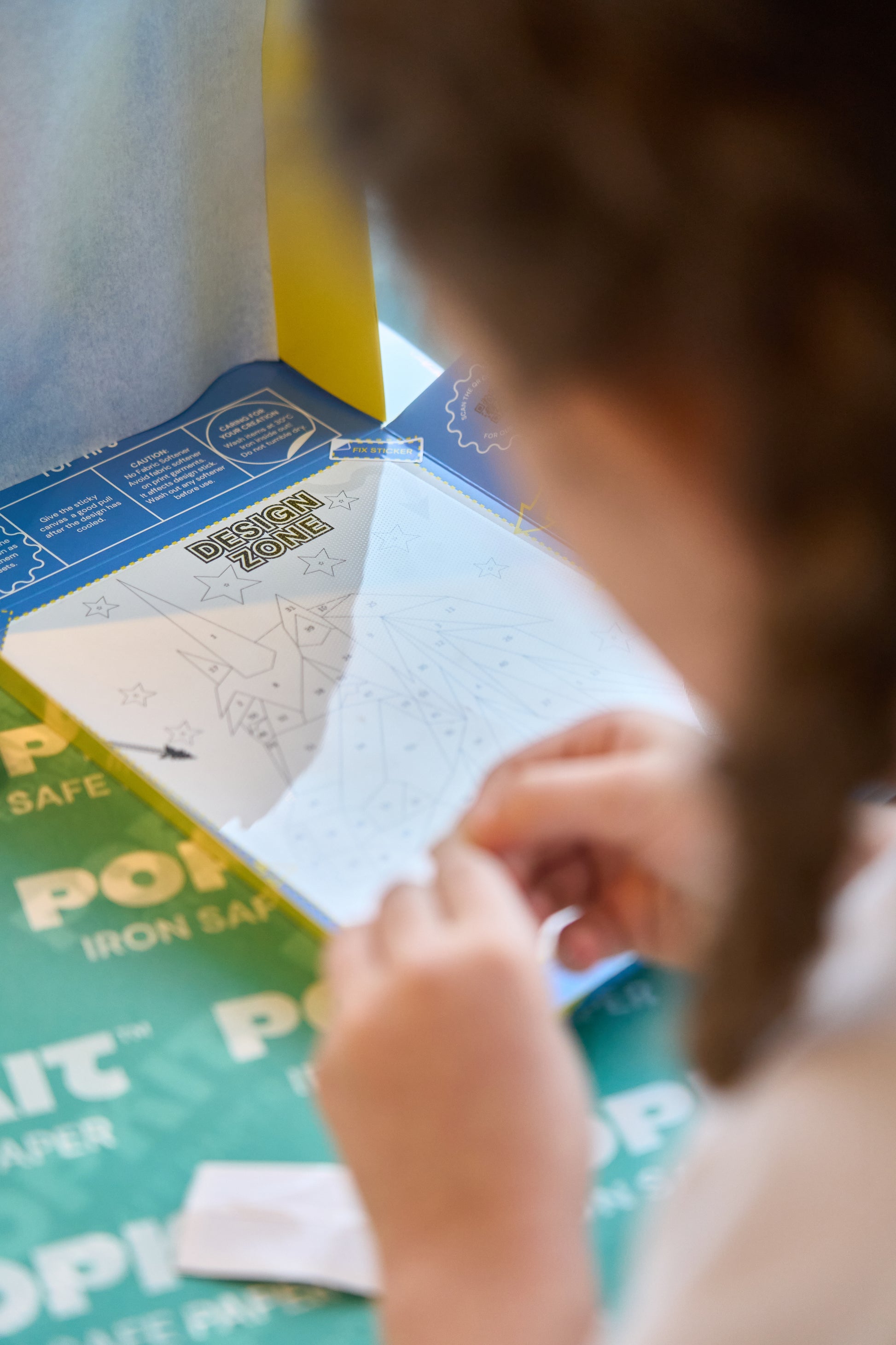 A child putting together the various coloured pieces of the peel and print Pop Kit Unicorn kit.