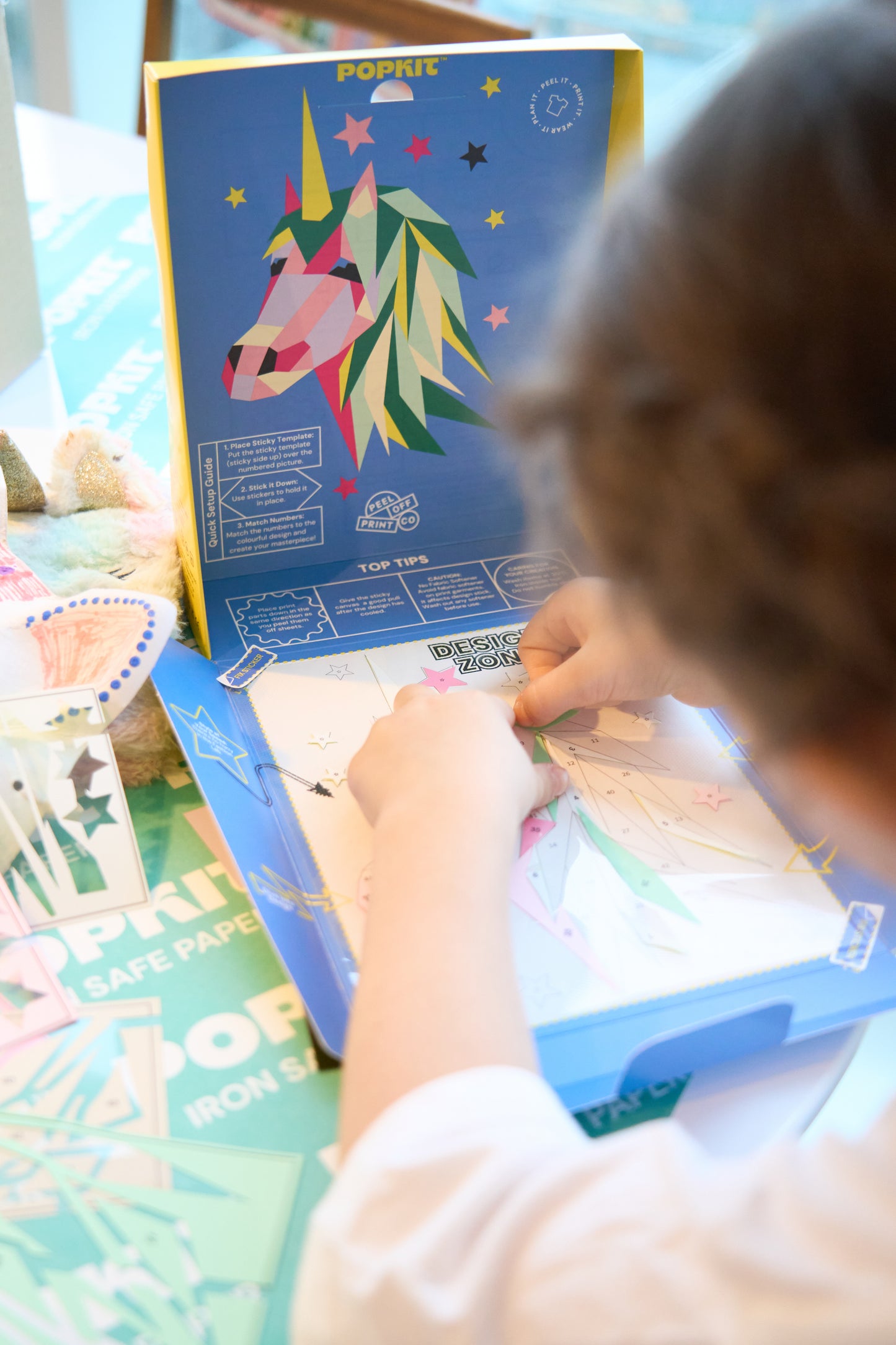 A child putting together the various coloured pieces of the peel and print Pop Kit Unicorn kit.