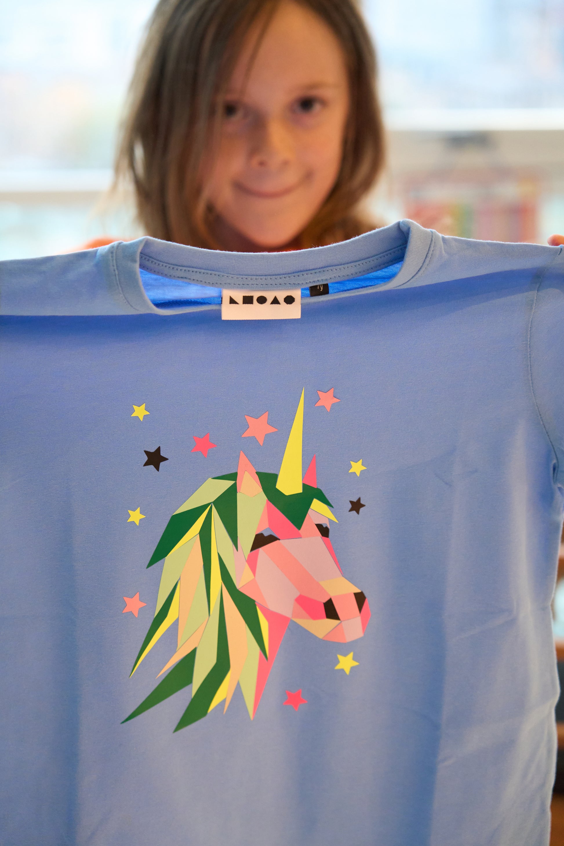 A child shows her finished creation of a Unicorn peel off and print Popkit  on her tshirt.