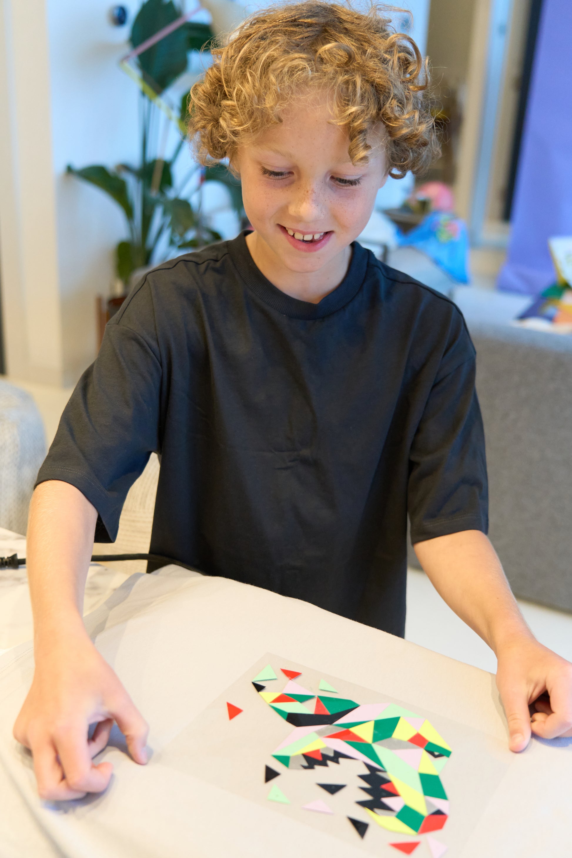 A child with the Dinosaur Pop Kit, with the assembled dinosaur on a jumper ready to iron on.