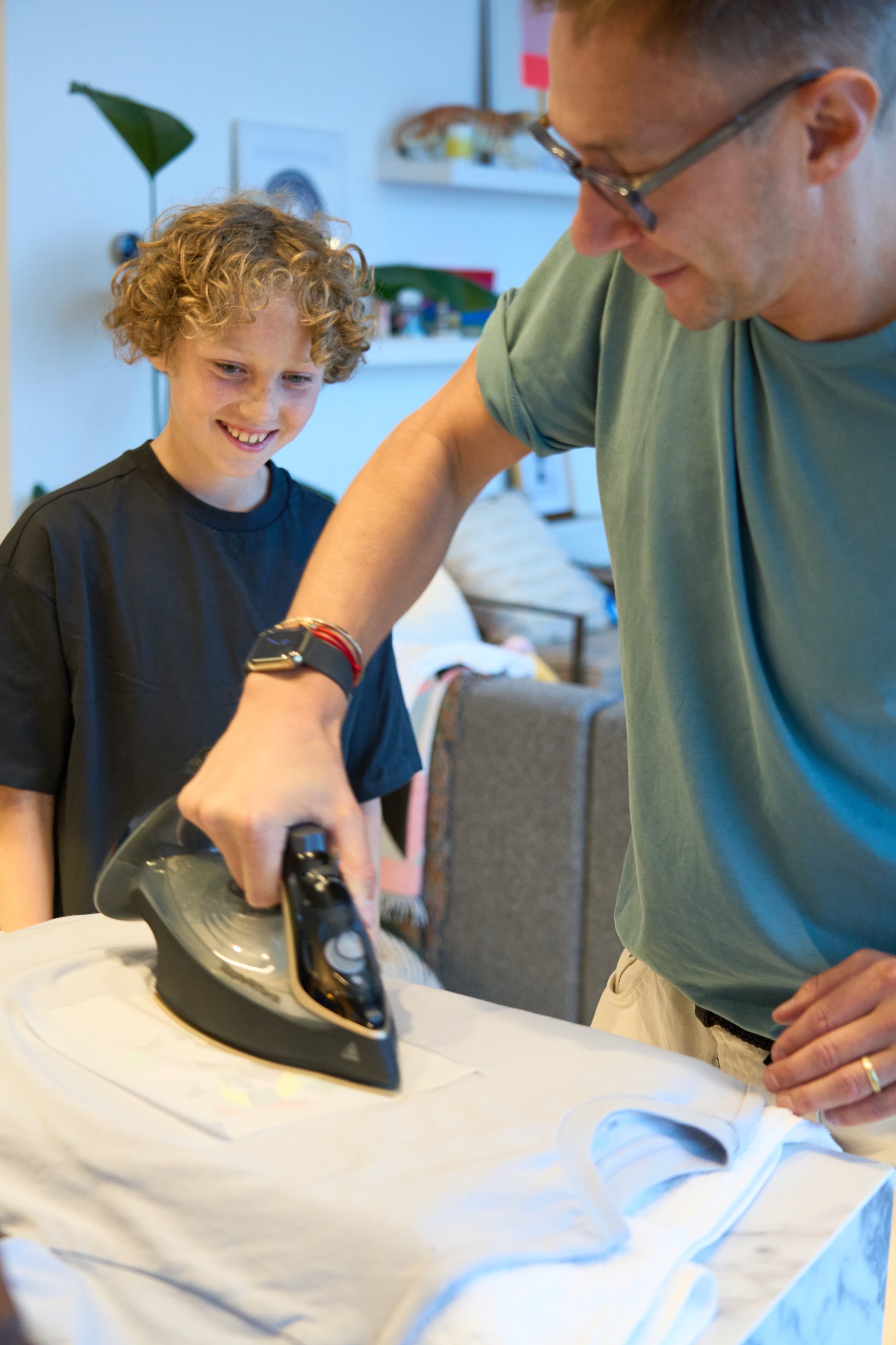 An adult irons on the Dinosaur Pop Kit as the child smiling looks on.