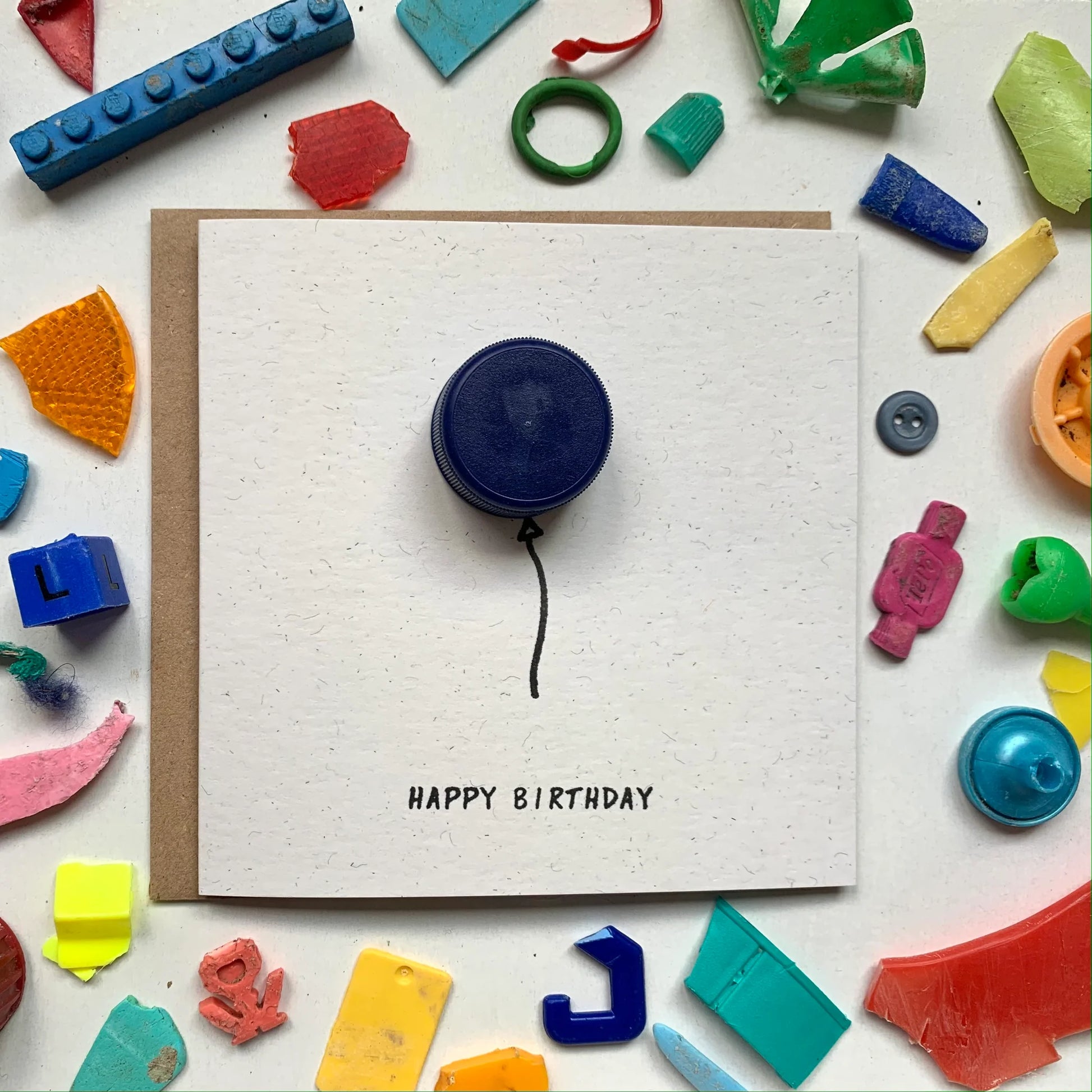 Sustainable Birthday card using washed up micro plastics found by the River Thames. Featuring a balloon which is a plastic bottle top and ink drawing.