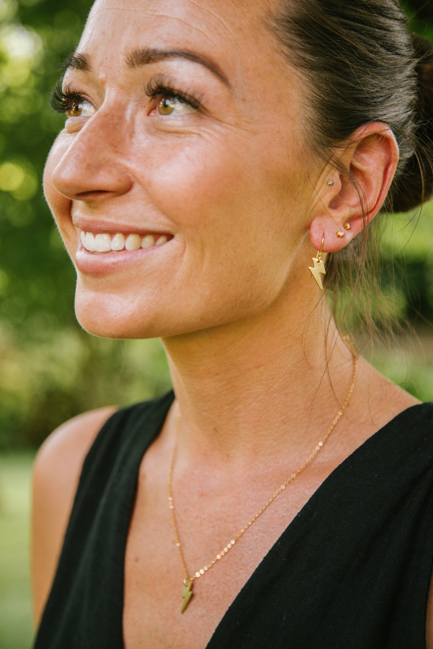 Gold-plated Lightning Bolt necklace, hanging on a matching 18" gold-plated chain. The lady is wearing matching Gold-plated Lightning Bolt earrings.