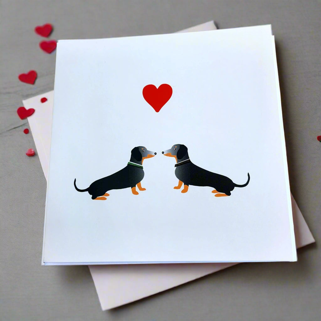 Two Dachshund's nose to nose with  a red heart above their head