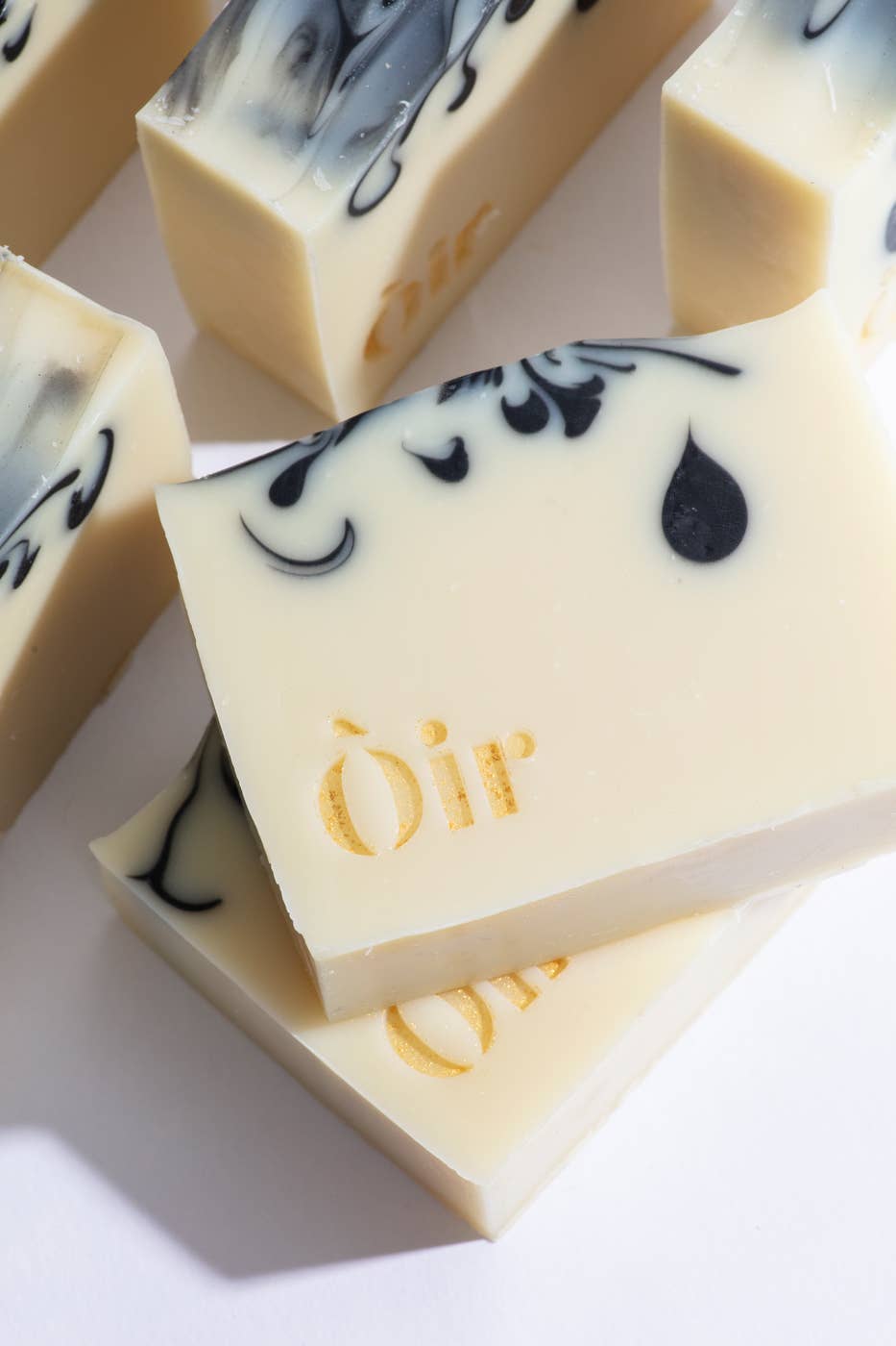 Cedarwood, Clary Sage, Rose Geranium and Vetiver Soap. Handmade in the UK. A sustainable replacement for shower gel. The soap is a cream bar with beautiful, gold lettering with the word OIR| and black swirls in the soap.