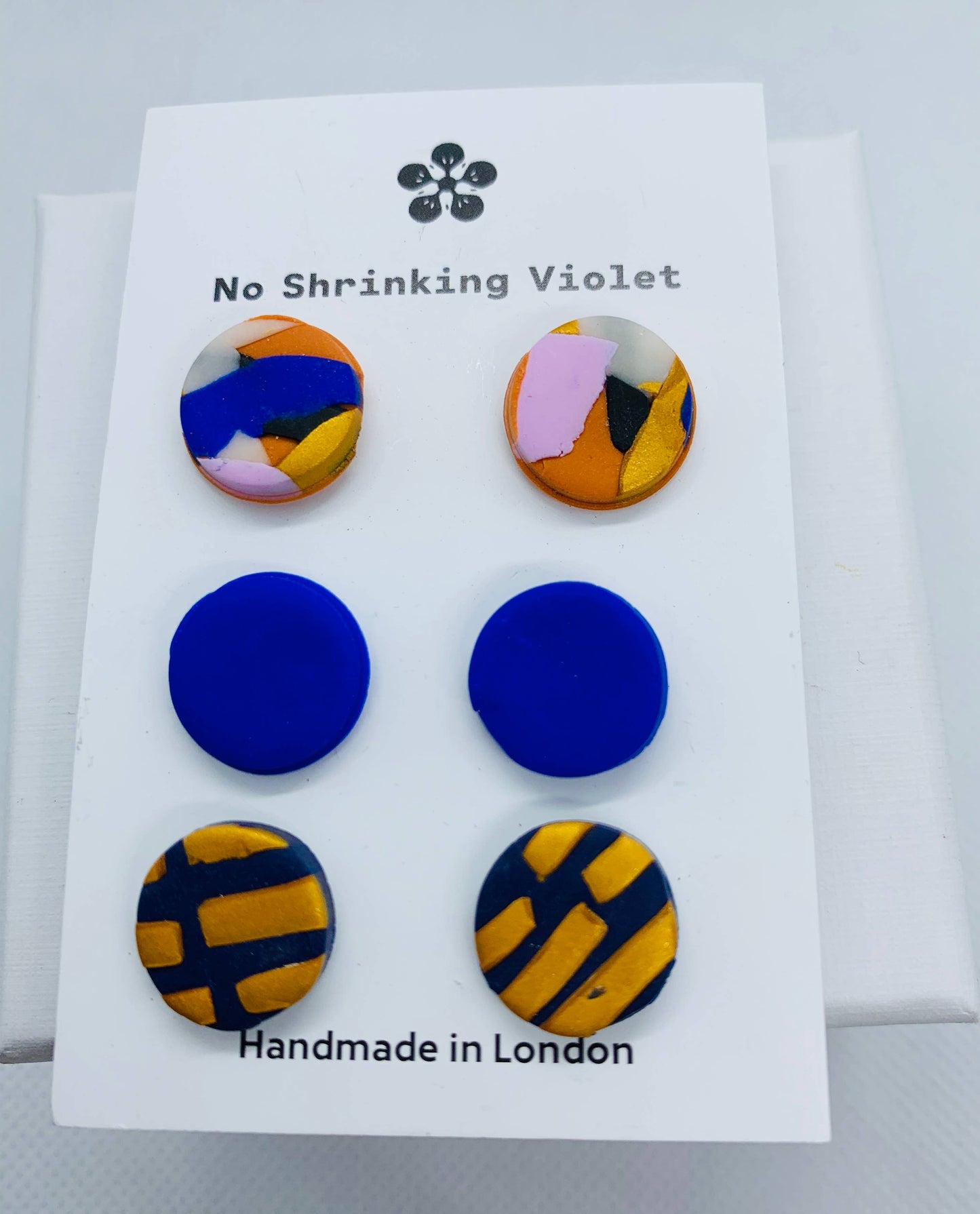 Three fabulous pairs of polymer clay studs, with silver plated nickel-free posts. and rubber stoppers. In gorgeous blues, yellows and pinks reminiscent of No Shrinking Violet's designer's upbringing in her native Australia. One pair is an abstract mix of cobalt blue, pinks, orange, white and black. The second pair is cobalt blue and the last is navy background with mustard yellow shapes.