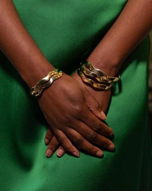 Classic and chic, but with a twist. AARVEN’s Kilifi bracelet bangle is an artistic adaptation of the traditional gold bangle. This timeless and elegant bracelet features a sleek wavy design and a bright gold tone finish. Ethically made in Kenya, recycled brass.