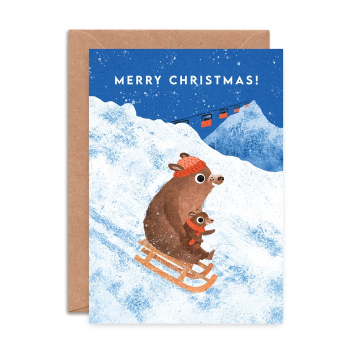 Illustrated Christmas greeting cards by Emily Nash Illustration. Snowy scenes of an adult and baby bear enjoying sledging With the words Merry Christmas!