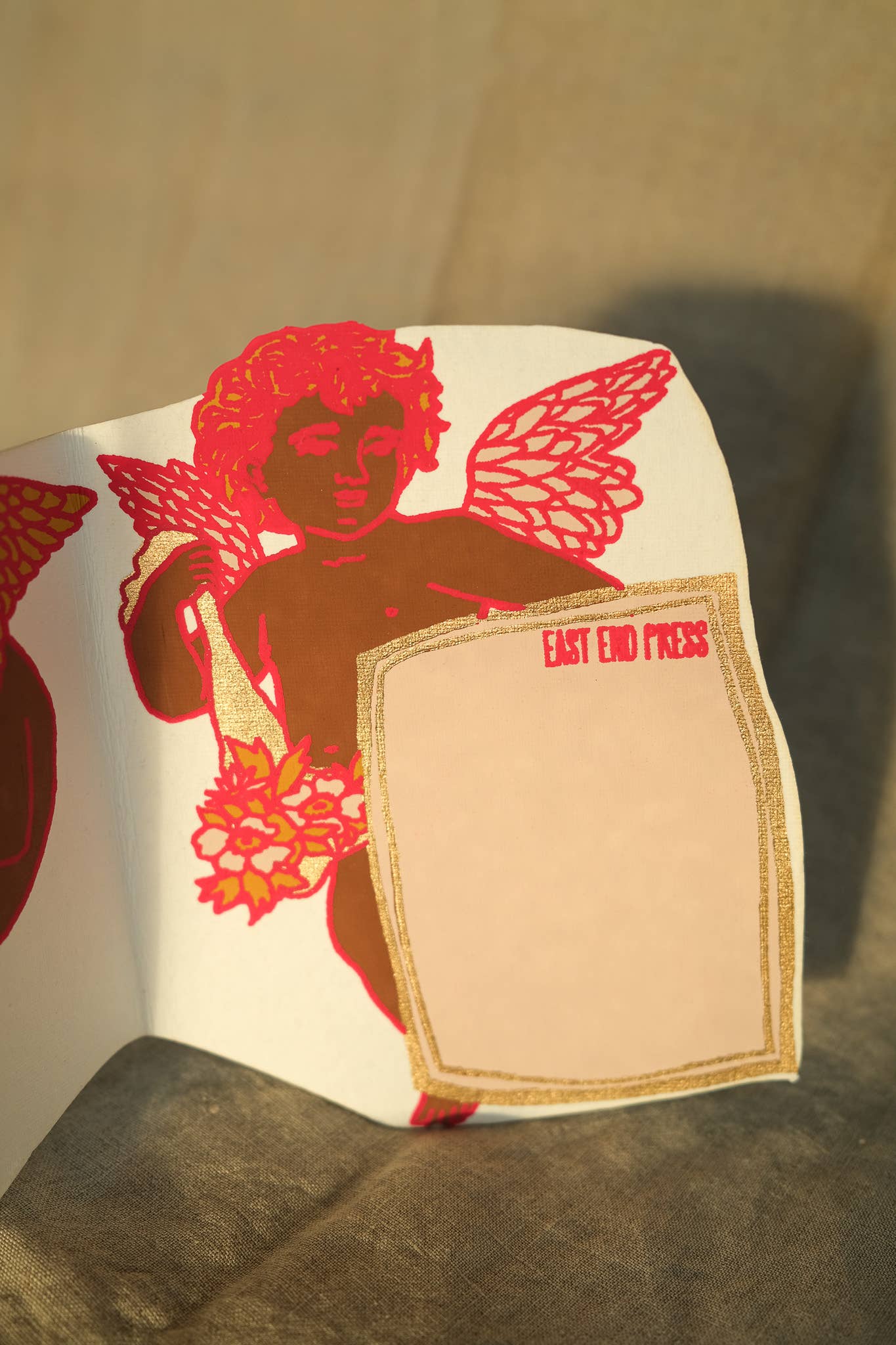 Cupid Concertina Card. This greeting card unfolds to reveal a row of cheeky cherubs. There is a panel for your message on the reverse, and a beautiful matching envelope with a luxe gold printed pattern.