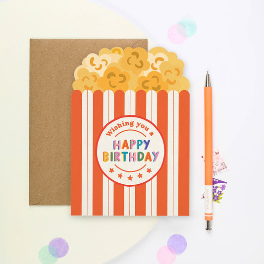 Add a sprinkle of fun to birthdays with our quirky Popcorn-Shaped Birthday Card. This unique greeting card, crafted in the shape of a classic red and white striped popcorn box, features whimsical illustrations of fluffy popcorn kernels, evoking the excitement of a movie night celebration. 