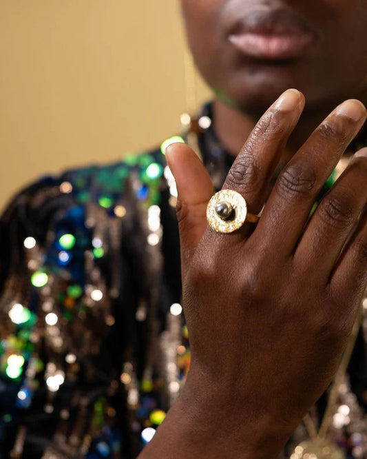 This Mombasa brass round ring is an elegant and striking signature piece. Ethically handmade in Kenya by our team of talented artisans. The brass is hand-hammered to give it a beautiful shimmer, making it an eye-catching accessory. The organic hammered texture and smooth aluminium ‘pearl’ makes this ring a wearable work of art.

Materials: Recycled Brass, Aluminium Pearl in the centre