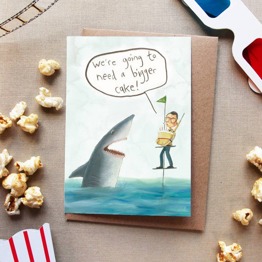 Chief Brody needs a bigger cake! Film fans of a certain age will appreciate the biting humour of this Jaws-inspired card.

Let’s make the water safe for sharks and human alike by keeping plastic out of it. This fun card is made from recycled paper and wrapped in fully biodegradable film.
Illustrated card, featuring Martin Brody bringing cake to his great white shark chum from Jaws.