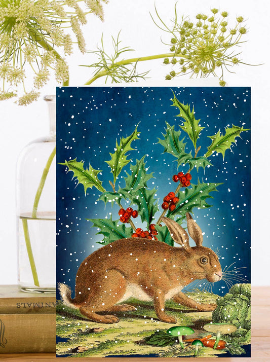 Vintage style card depicting a Hare, surrounded by holly and mushrooms under a dark snowy sky